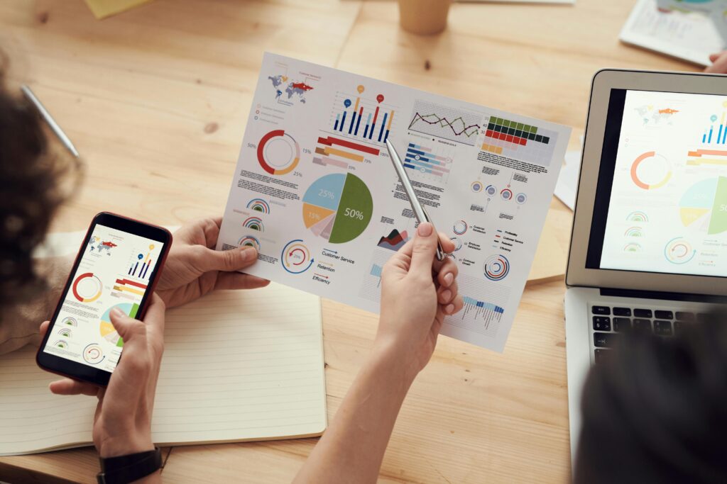 Hands holding analysis graphs on paper and on screens. CDP & CRM CareCloud includes analysis & reporting app.
