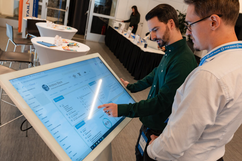 Two men interacting with a terminal CDP & CRM CareCloud exhibited CareCloud platform at Retail in Detail 2025.
